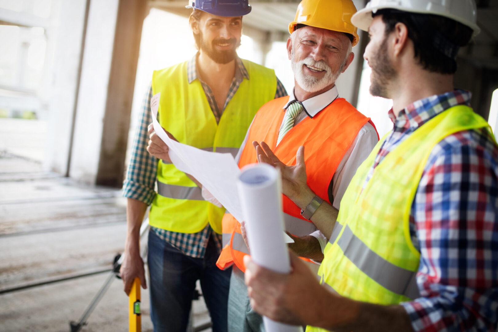 Three men in hard hats and safety vests talking.
